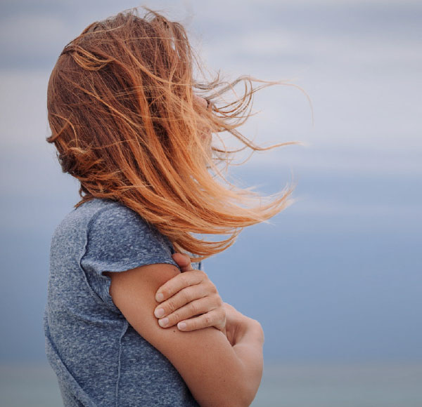 A young person hugging her arms and looking at the horizon