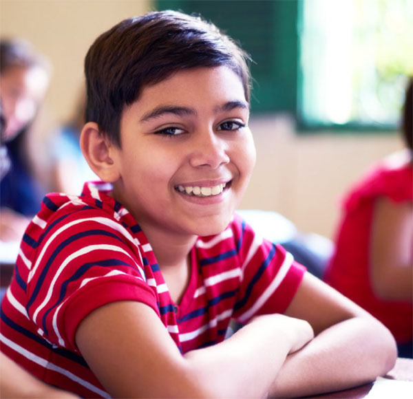 A smiling young person at a school desk