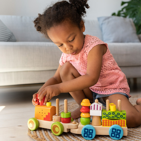 A young girl playing with a wooden train