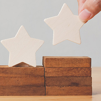 A hand places wooden stars on rising steps