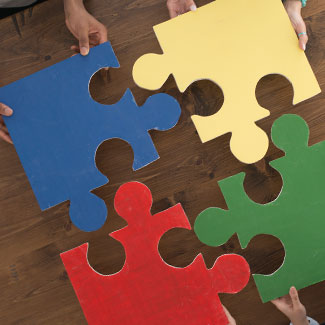Four people putting large puzzle pieces together