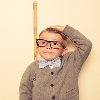 A small boy measures himself against a wall