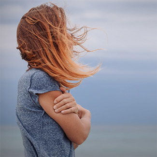 A woman hugging her arms and looking at the horizon