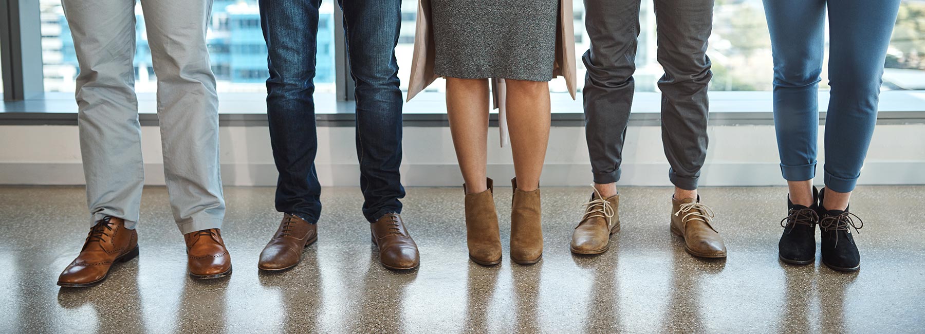 Cinq paires de pieds debout dans un bureau