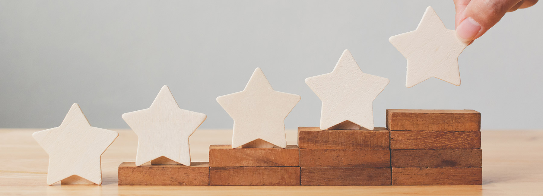 A hand places wooden stars on rising steps