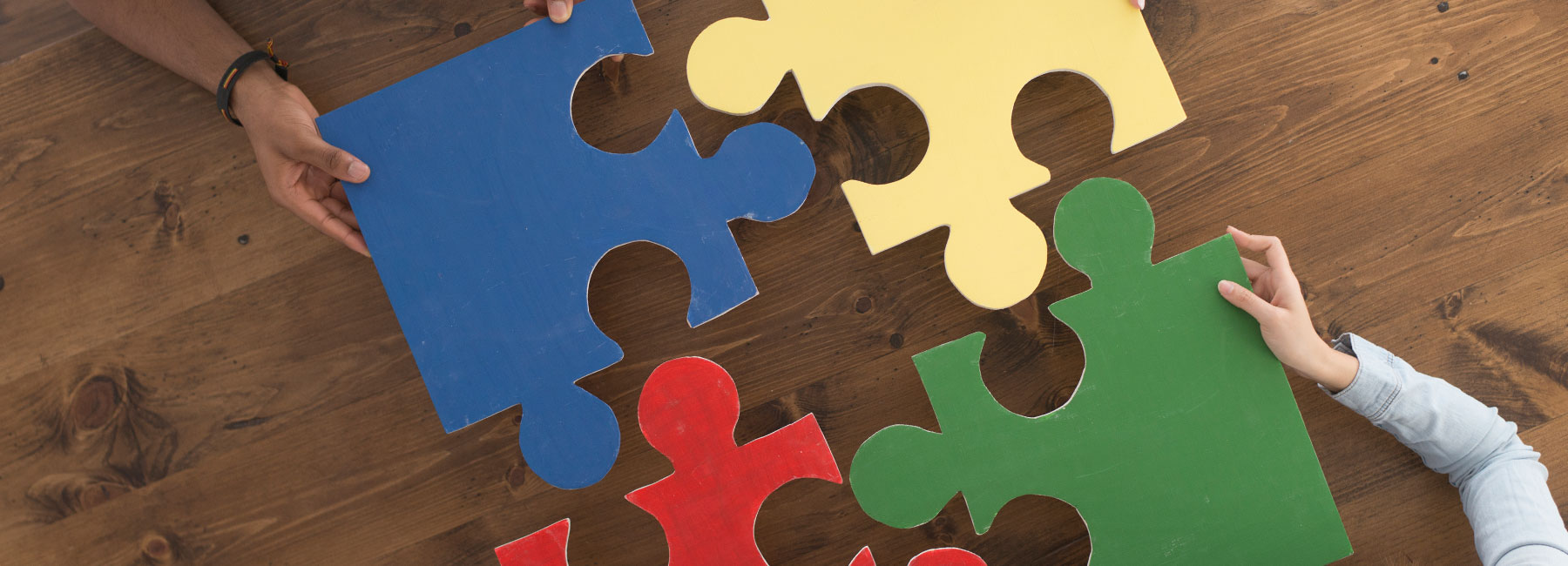 Four people putting large puzzle pieces together