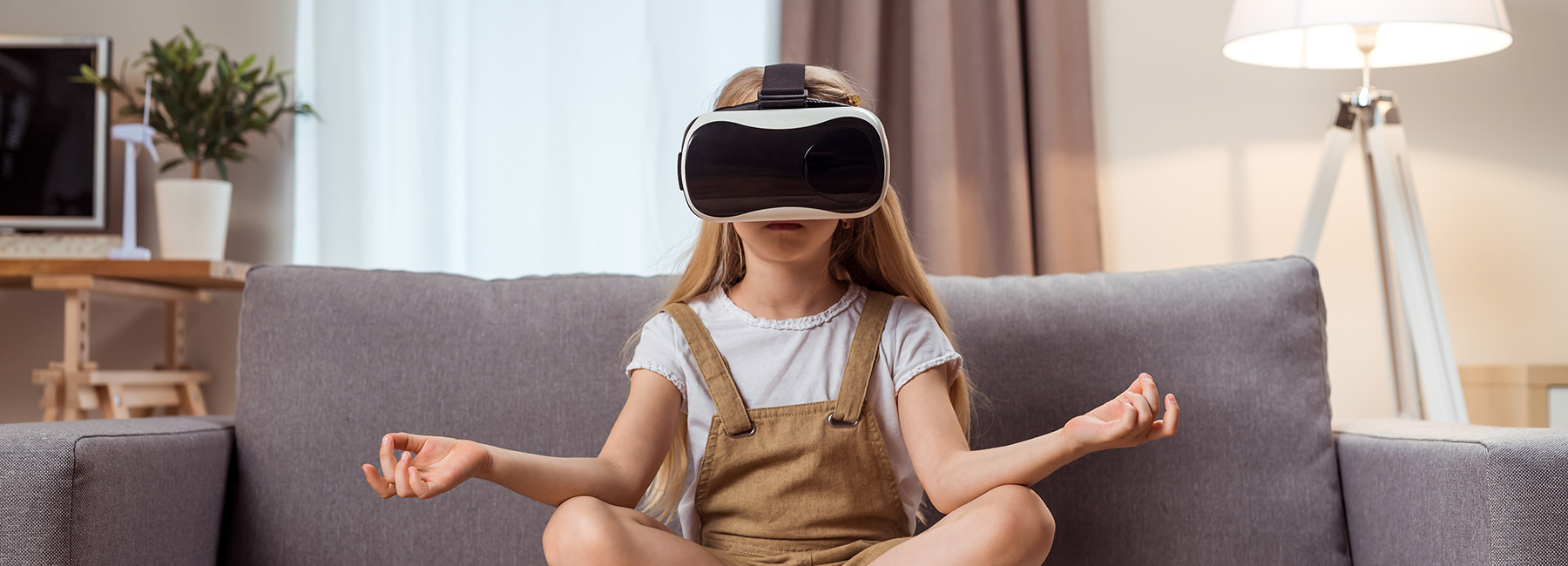 Girl meditating on a couch while wearing a virtual reality headset