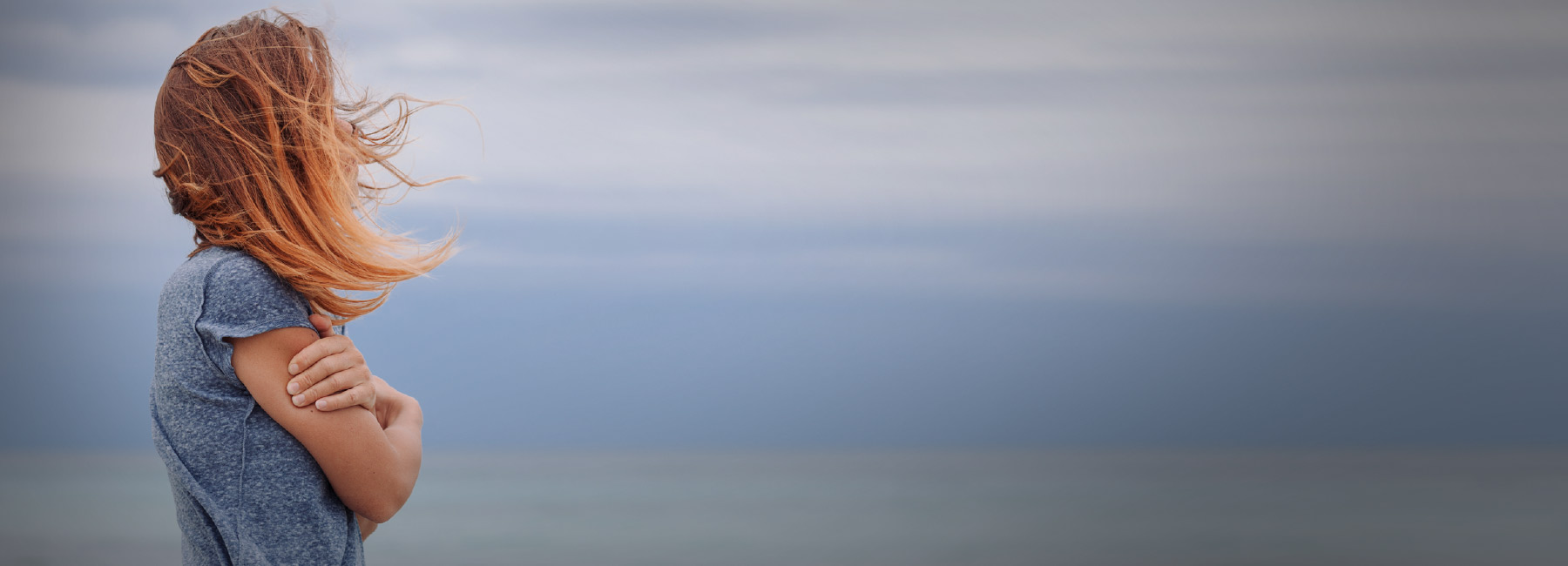 A woman hugging her arms and looking at the horizon