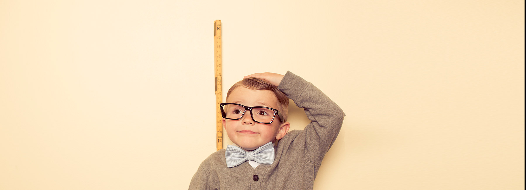 A small boy measures himself against a wall